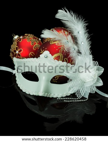 White mask and Christmas red balls on a black background