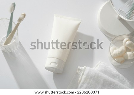 A glass containing toothbrushes decorated with a tube, table mirror, towel and several silkworm cocoons. Natural cosmetic concept. Empty label for branding mockup