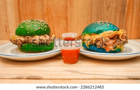 wide shot of two colored burgers on a wooden background