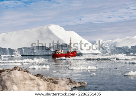 OCEAN ICEBERG WITH RED FISHING SHIP IN GREENLAND Royalty-Free Stock Photo #2286251435