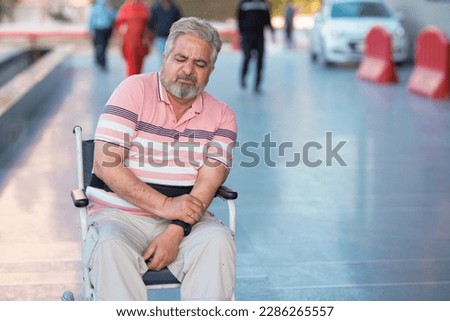 Indian old man sitting on wheel chair and moaning pain. Royalty-Free Stock Photo #2286265557