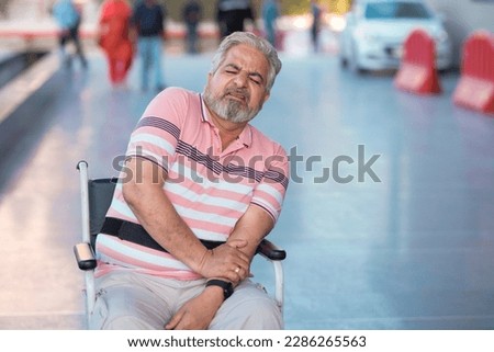 Indian old man sitting on wheel chair and moaning pain. Royalty-Free Stock Photo #2286265563