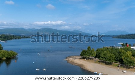 View over Loch Lomond from Lomond shores on a sunny summer day in Scotland, with people participating in water sports, Balloch, Scotland Royalty-Free Stock Photo #2286279289