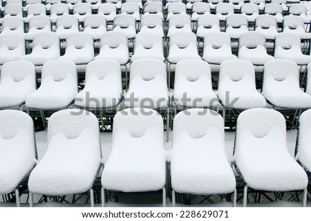 Empty stadium chairs in a row covered with snow.