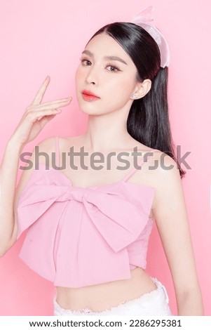 Cute Asian woman model gathered in ponytail with korean makeup style on face have plump lips and clean fresh skin wearing pink camisole on isolated pink background. Royalty-Free Stock Photo #2286295381