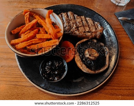A meal from TGI Fridays of a sirloin steak, grilled tomato and mushroom, sweet potato fries and Jack Daniels glaze
