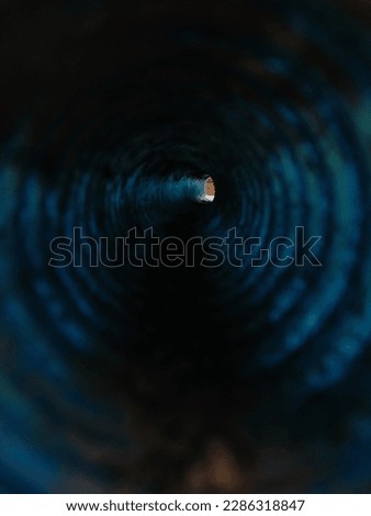 Selective focus. The blue plastic pipe is dirty and dark. Photo taken from inside the pipe. 