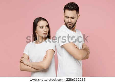 Young irritated dissatisfied couple two friends man woman in white basic t-shirts quarrel swearing have problem stress need family psychologist isolated on pastel pink color background studio portrait Royalty-Free Stock Photo #2286332235