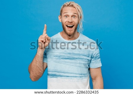 Young happy insighted smart proactive blond man with dreadlocks 20s he wear white t-shirt holding index finger up with great new idea isolated on plain pastel light blue background studio portrait.