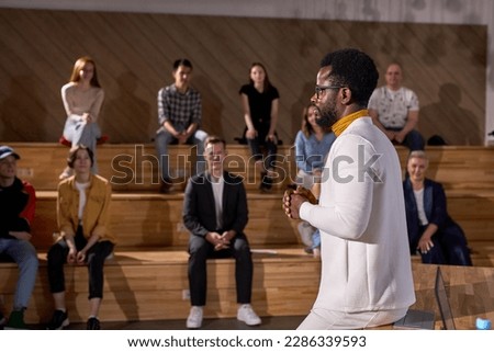 male african-american speaker giving presentation in lecture hall, audience. Young participants students in the background. Conference event, training. Education, diversity, inclusive concept. Royalty-Free Stock Photo #2286339593