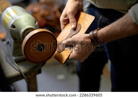young man working on Electric Leather Burnisher Machine, close up side view cropped shot Royalty-Free Stock Photo #2286339605