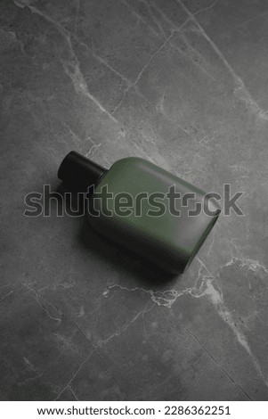 Green perfume bottle with grey marble background