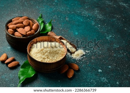 Almonds and almond flour in bowls. On a dark textured background. Copy space.