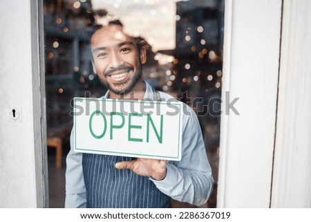 Asian man, small business and portrait with open sign on window for service in coffee shop or restaurant. Happy male entrepreneur holding billboard, poster or welcome for opening retail store or cafe