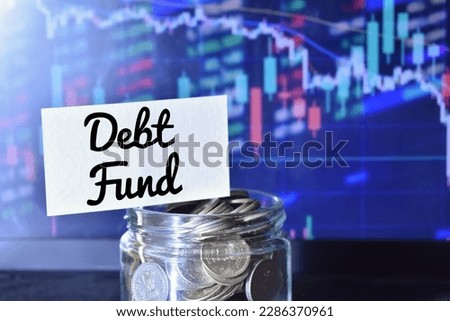 A closeup picture of a pot of coins with a label with text Debt Fund against a candle and stick chart in the background