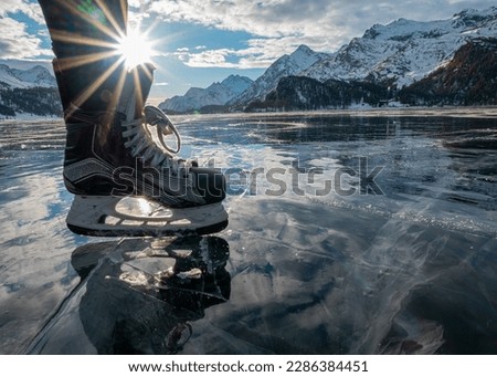 Ice skating in the sun on a frozen lake in Sils (Engadin) in the January with mountains in the background.