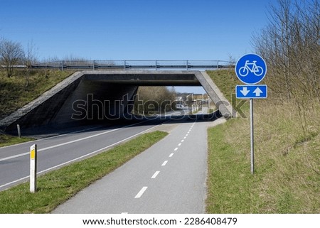 The bike path runs alongside the main road. Cycling infrastructure. The sign indicates the passage by bicycles only.