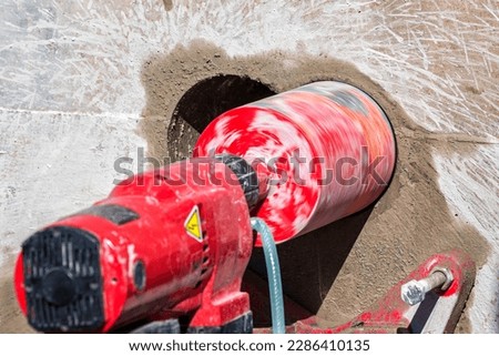 Worker is drilling to concrete wall with core drill machine. core drill is a drill specifically designed to remove a cylinder of material, much like a hole saw. The material left inside the drill bit. Royalty-Free Stock Photo #2286410135