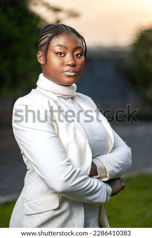 image of a posed african lady outside- black lady with a crossed arms looking to camera