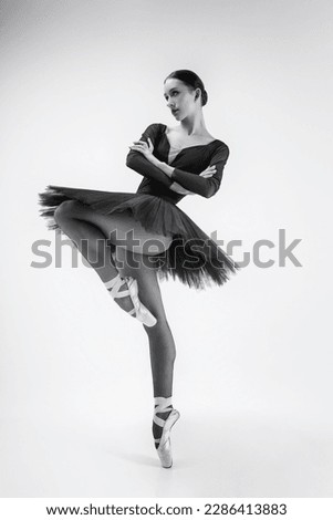 a ballerina in a black tutu stands with her arms crossed on her chest