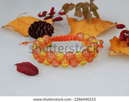 Beautiful friendship bracelet on a white. Colorful bracelet and leafs