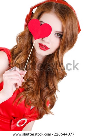 portrait of joyful cheerful cute woman with red hair and red lips holding red hearts in hands in red headphones on head. portrait of attractive woman isolated on white studio shot. Valentine's Day.
