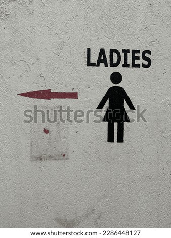 Hand painted wall sign for directions to a ladies restroom or bathroom