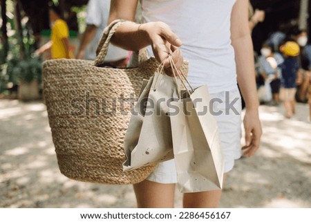 Woman holding a woven bag from Natural materials, and paper bags, shopping at local markets in Thailand, using natural renewable materials and sustainability lifestyle concept.