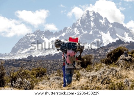 Mount Kilimanjaro with native porters carrying pack on their heads Royalty-Free Stock Photo #2286458229