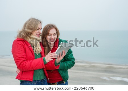 Two women enjoy a digital tablet on the nature
