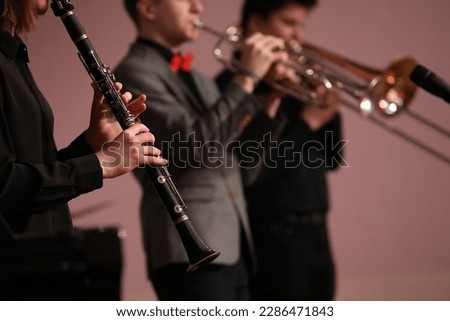 Band of musicians playing wind instruments hand holding a black clarinet close-up