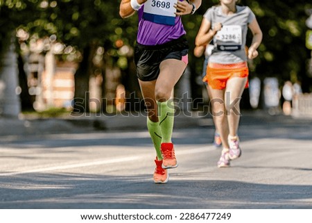 legs female runner athlete run marathon race on city street, legs woman jogger in compression socks