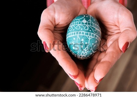 The girl holds an Easter egg in her palms. Place for text. Easter theme.