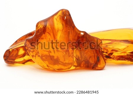  Transparent polished amber on a white background. Copal. Ancient fossil resin. Precious mineral. Patterns in amber. Natural material for jewelers. Science and geology. Royalty-Free Stock Photo #2286481945
