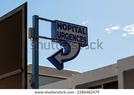 Street sign saying in french "Hopital Urgences", meaning in english, "Hospital Emergency".