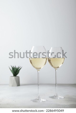 Glasses of white wine and small green flower on light board. Royalty-Free Stock Photo #2286495049