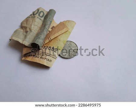 Crumpled rupiah banknotes and rusty dirty coins isolated on white background.