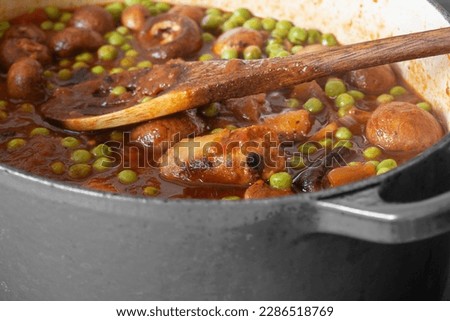 Sausage casserole in a casserole dish, with potato, mushrooms, tomatoes, peas and onion, in a beef stock.