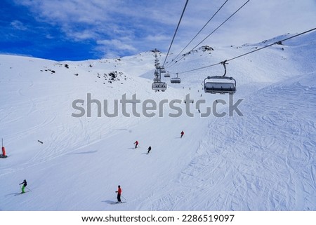 Snowy ski track in the mountains above Les Ménuires ski resort in the French Alps, as seen from a chairlift Royalty-Free Stock Photo #2286519097