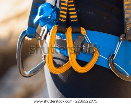 A man with climbing equipment, with easy-clipping carabiners and quick draws, hiker stands against the background of mountains and  rocks, is engaged in extreme sports and rock climbing.