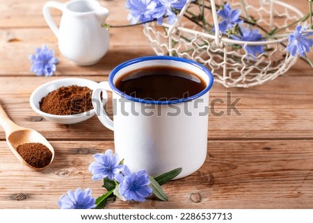 Drink made of chicory roots in cup, blooming chicory plants and spoon with granulated chicory root powder on brown wooden table. Caffeine free alternative to coffee. Royalty-Free Stock Photo #2286537713