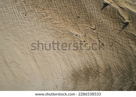 Top view of the sandy beach with a beautiful pattern formed from the water, in the bright sunset light in summer. Photograph with drone in the form of texture and background