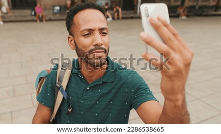 Young man tourist takes photo on cellphone while standing on the square of the old city