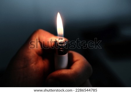 Lighter hand flame in the dark. hope and sadness Royalty-Free Stock Photo #2286544785