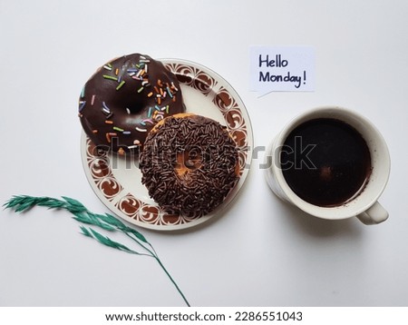 Donuts, a cup of coffee, text hello monday on a white background.