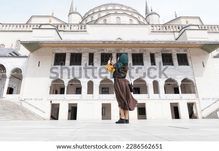 Middle Eastern young woman taking photo with phone. mosque photo jacket muslim woman