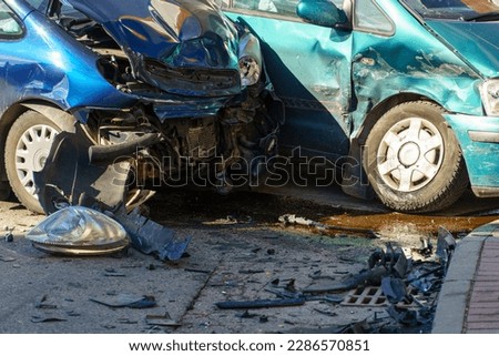 Car accident. Two crashed passenger cars are on the road after the accident. Various parts of the vehicle are lying on the road, the broken hood and windshield.