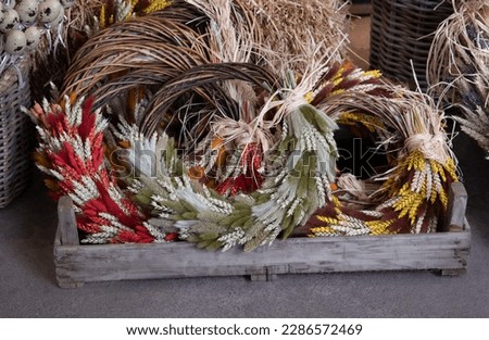 Easter door wreaths made of colorful dry rabbit bunny tales grass and ears of wheat in greek florist shop for sale. Easter floral decoration. Horizontal. 