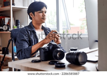 Potrait of young photo editor enjoying coffee while editing photo or video in front of the screen computer, sitting at photo and video production office
