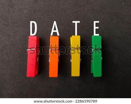 Colored wooden clips with word DATE on black background
